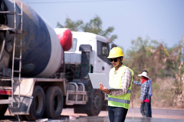 Asian supervisors use laptops on construction sites on sunny days.