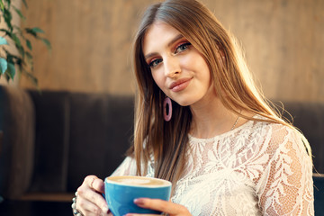 Nice young woman enjoying cup of coffee in a coffee shop