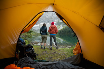 Female friends looking at lake view outside camping tent