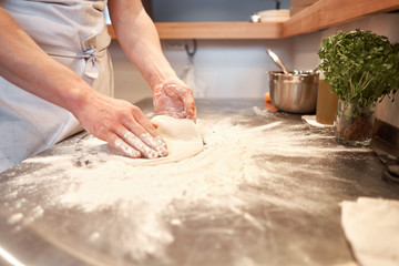 Obraz na płótnie Canvas Dough for Neapolitan pizza, the chef rolls out the blanks. Closeup hand of chef baker in uniform white apron cook pizza at kitchen