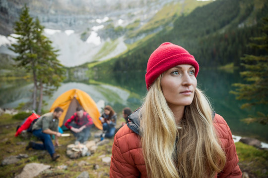 Pensive woman camping with friends looking away