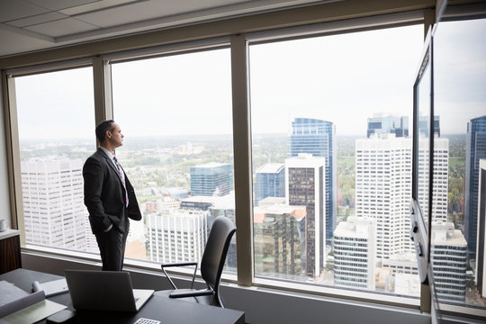 Pensive Businessman Looking Out Over City From Conference Room Window