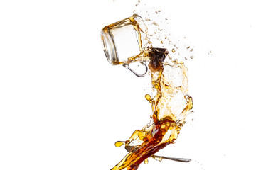 transparent mug with black tea turned upside down and falls with a splash and spray