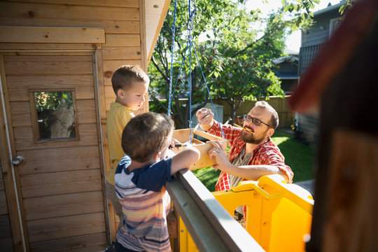 Father And Sons Repairing Treehouse