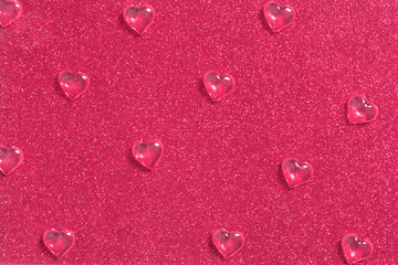 Crystal drops of glassy hearts on shiny glitter background 
