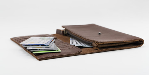 Brown wallet with credit cards and hundred dollar bills on white background