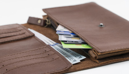 Brown wallet with credit cards and hundred dollar bills on white background. Close-up