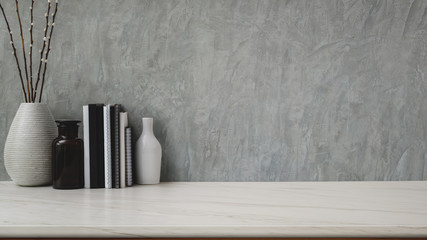 Close up view of workspace with copy space, ceramic vases and books on marble desk with  grey loft...