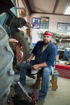 Portrait Confident Mechanic Working On Tractor In Workshop