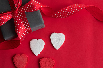 red and white hearts and a gift box with a red ribbon in a white dot on a red background on an abstract background