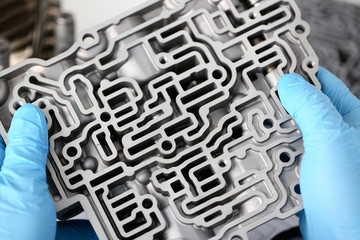 The auto repair service repairman in automatic gearboxes holds in his hand in blue protective...