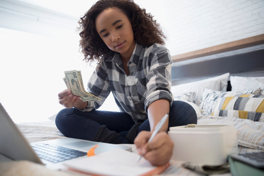 Teenage Girl Managing Personal Finances At Laptop On Bed