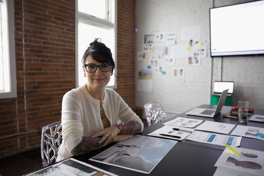Portrait smiling confident female designer reviewing proofs in conference room