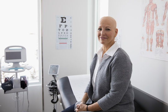 Portrait smiling, confident bald female cancer patient waiting in clinic examination room