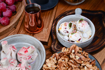 Sweet khinkali, churchhela, ice cream and nuts served on a table. Turkish coffee in traditional embossed cup cezve.