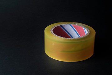 Rolled adhesive tape at black background