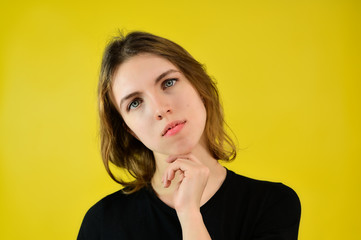 Close-up Studio portrait of a pretty blonde girl in a black T-shirt on a yellow background with bright emotions. A universal concept, the picture is suitable for any topic.