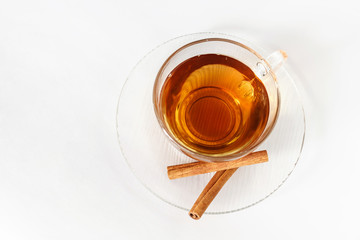 Glass cup of tea with cinnamon sticks. White background. Isolated. Top view. Hot spiced cinnamon tea.