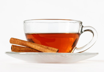 Glass cup of tea with cinnamon sticks. White background. Isolated. Close up. Hot spiced cinnamon tea.