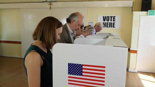 Voters voting at Polling Place / Station. People Stood at booths, choosing who to vote for and post Ballot papers in Box. USA Election