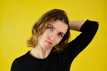 Close-up Studio portrait of a pretty blonde girl in a black T-shirt on a yellow background with bright emotions. A universal concept, the picture is suitable for any topic.