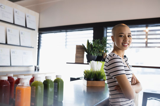Portrait confident teenage girl with shaved head working at juice bar