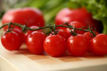 Cherry tomatoes lie on a cutting board in kitchen against backdrop of greenery healthy eating concept