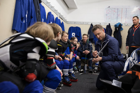 Attentive boy and girl hockey players listening to coach in locker room