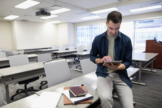 Businessman using digital tablet in empty classroom