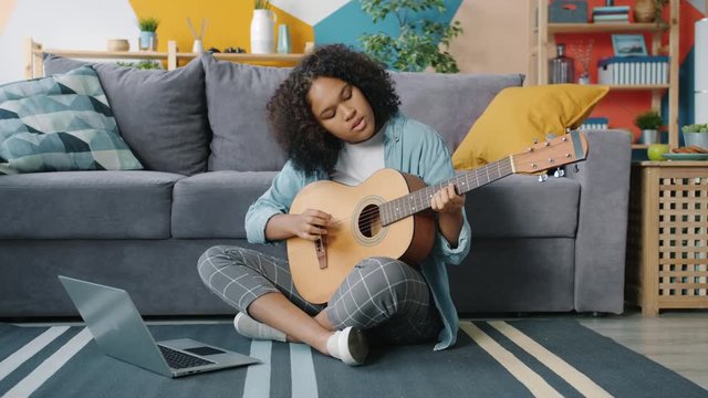 African American Teen Learns To Play Guitar With Online Tutorial