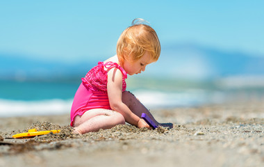 Fototapeta na wymiar little cute girl playing in the sand
