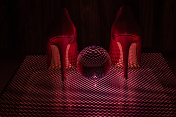 glaskugel auf einem lochblech mit roten high heels
