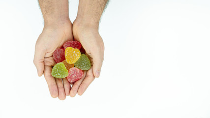 Multicolored, sweet, tasty marmalade in men's hands on white background
