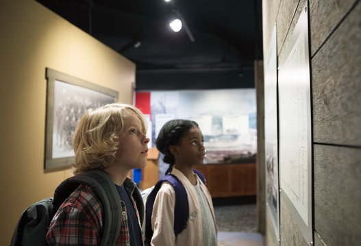 Curious multi-ethnic students looking up at exhibit on field trip in war museum