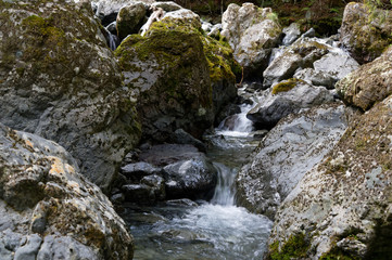 Naklejka na ściany i meble A river makes its course through rocks as it cascades down the river