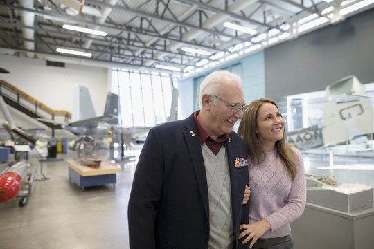 Senior war veteran father and daughter walking in war museum hangar