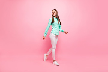 Fototapeta na wymiar Full length photo of funny pretty lady walking down street enjoy sunny day weather wear specs turquoise shirt white trousers isolated pink color background