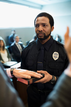 Male bailiff holding bible for witness in legal trial courtroom
