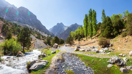 Scenic  panorama of sunny day on hiking track around among Fann mountains, Tajikistan. Stormy river runs down from of slope mountains.