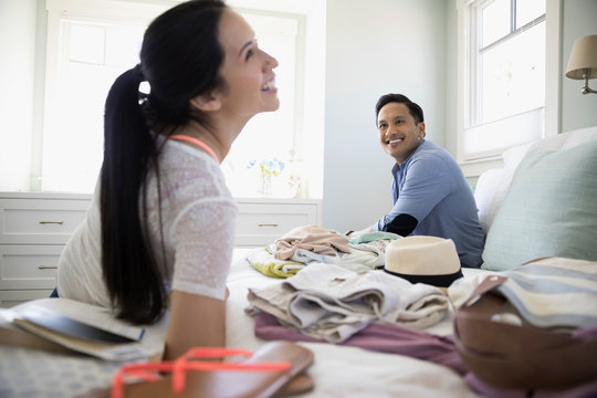 Smiling Couple Packing For Vacation On Bed