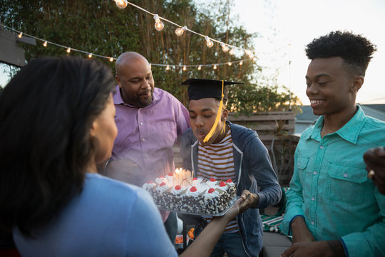 African American family celebrating graduation with cake on summer deck