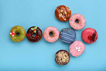 Sweet colored donuts on a blue background, laid out in the form of various geomitric figure, arrow,...