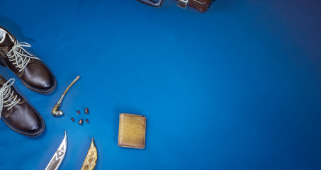 flat lay layout of men's leather accessories. Leather high boots with a knife in the bootleg - a symbol of hunters and brutality, military subjects on a dark blue background - classic blue