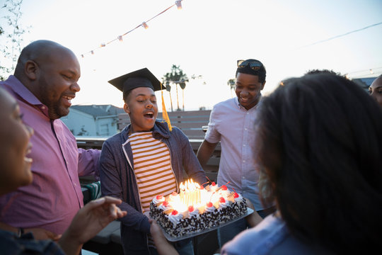 African American family celebrating graduation with cake on deck