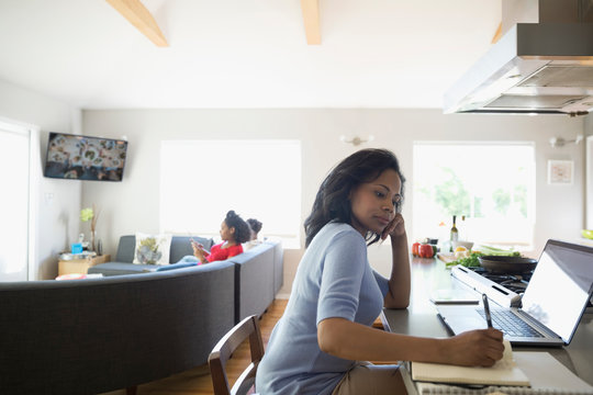 African American woman working at laptop in kitchen