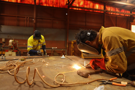Arc welders wearing safety welding glove, eyes protection performing welding at the construction fabrication table site workshop 