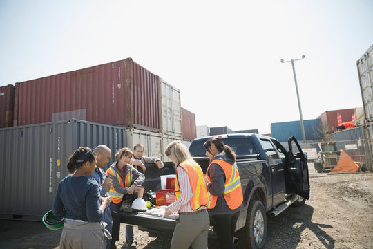 Workers enjoying lunch break at truck in sunny industrial container yard