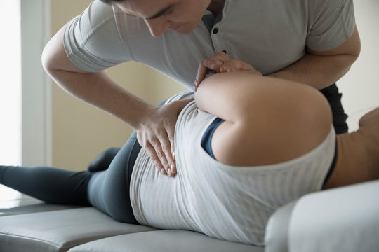 Male chiropractor adjusting woman on clinic examination table