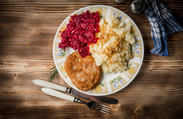 Pork cutlet with minced meat served with boiled potatoes and beetroot.
