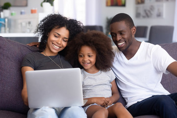 Happy African American family relax on couch with laptop